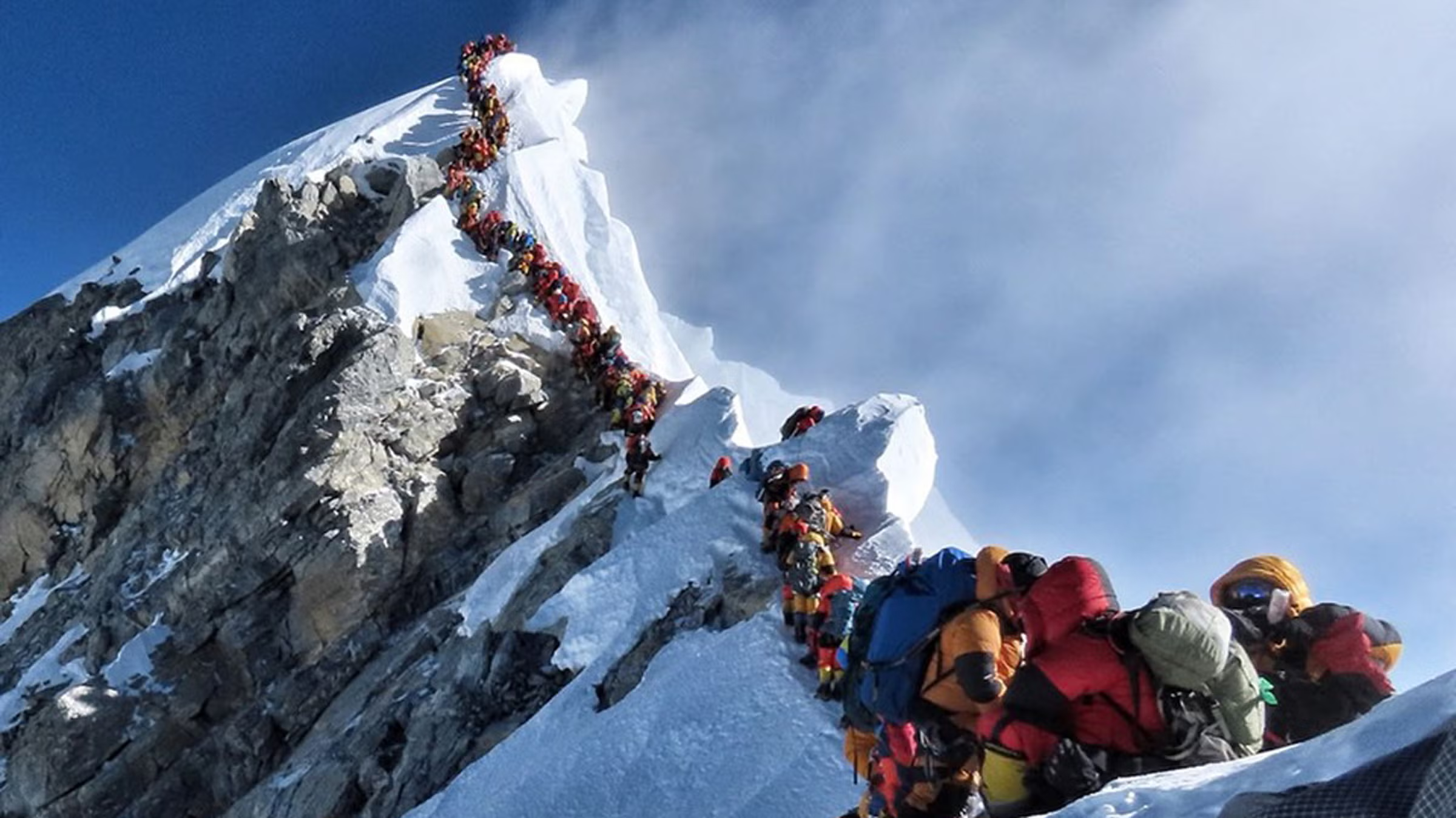 A long line of hikers waiting for their turn to get to the summit of everest
